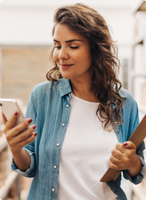 Business owner looking at phone with clipboard in hand
